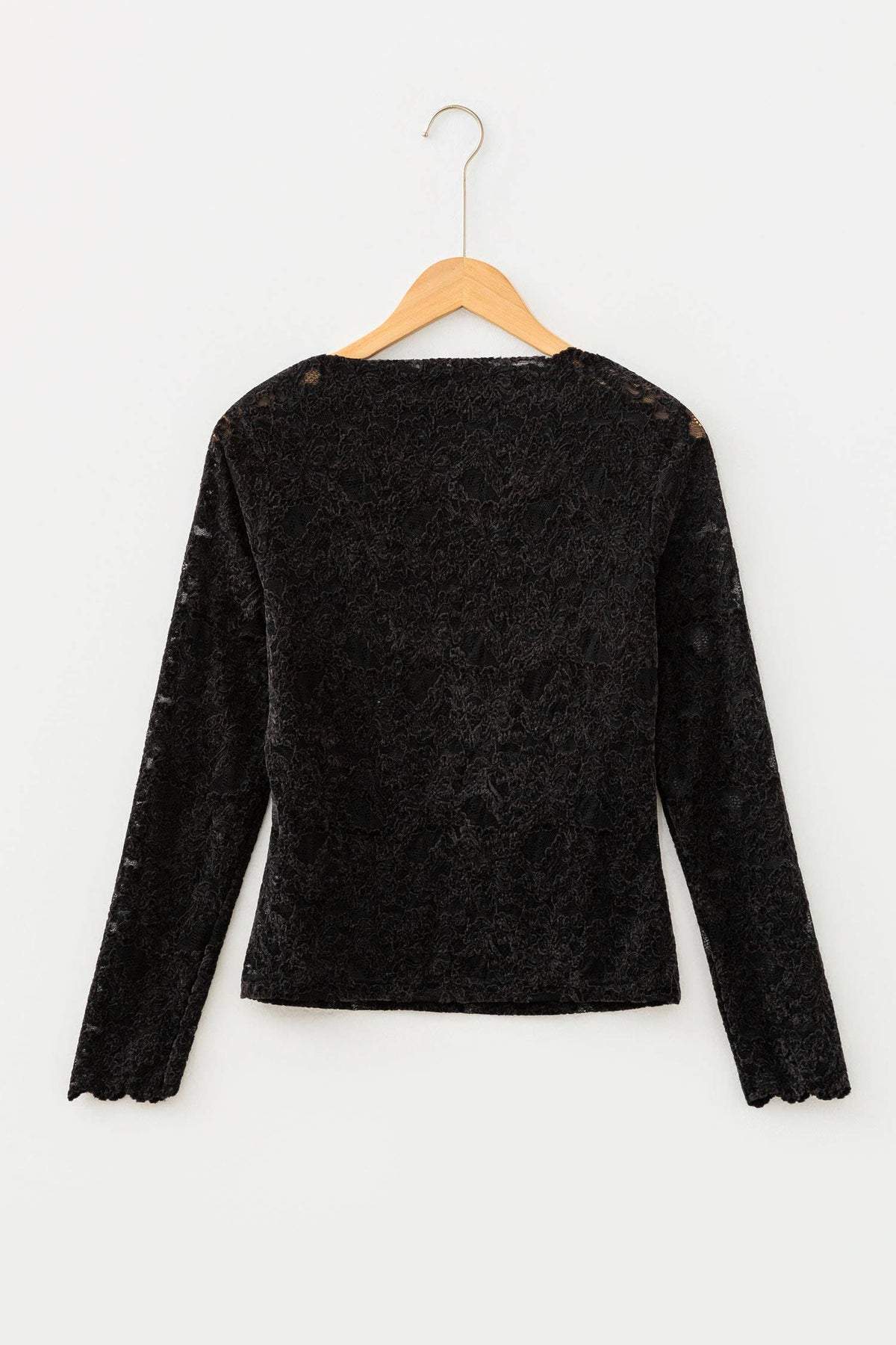 A black textured lace long-sleeve top hanging on a wooden hanger against a plain white background.