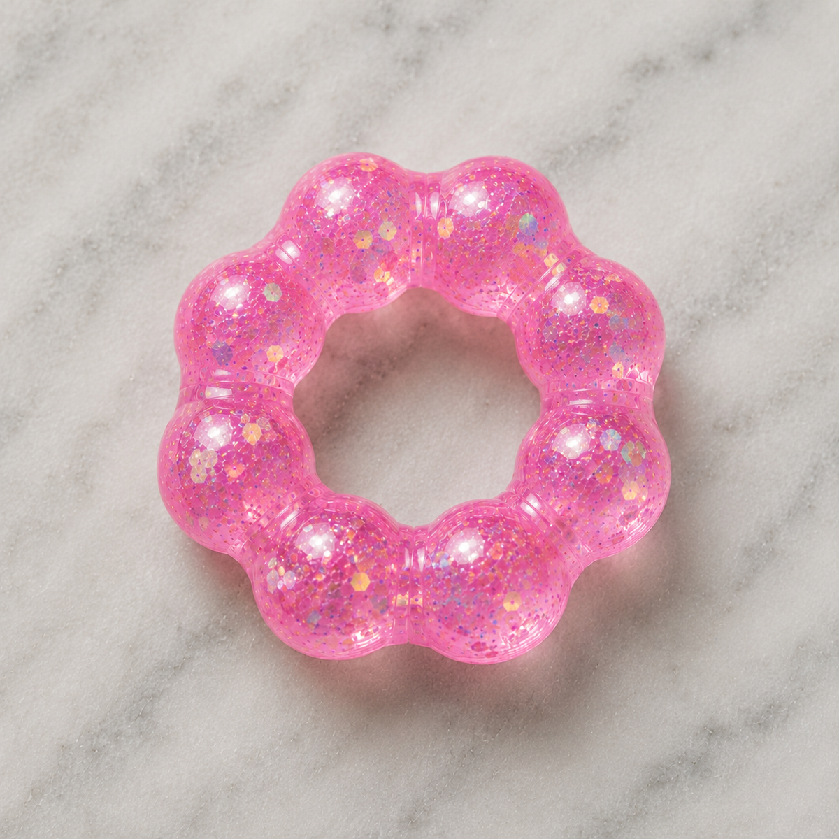 Pink glittery squishy bracelet on a marble surface.