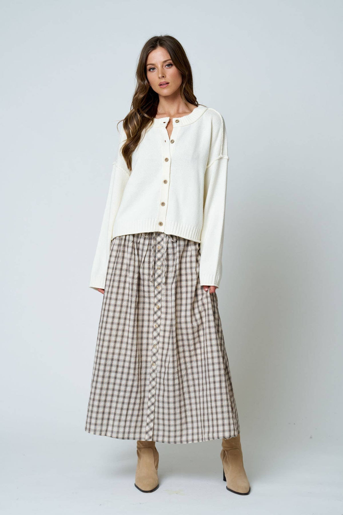 Woman wearing a white blouse and plaid skirt on a plain background