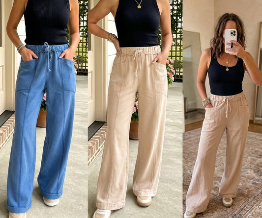Three-panel collage showing a woman modeling wide-leg drawstring pants in two colorways: a medium blue pair on the left and a light beige pair in the center and right. She wears a black ribbed tank top and white sneakers in indoor settings with visible architectural details and mirrors.