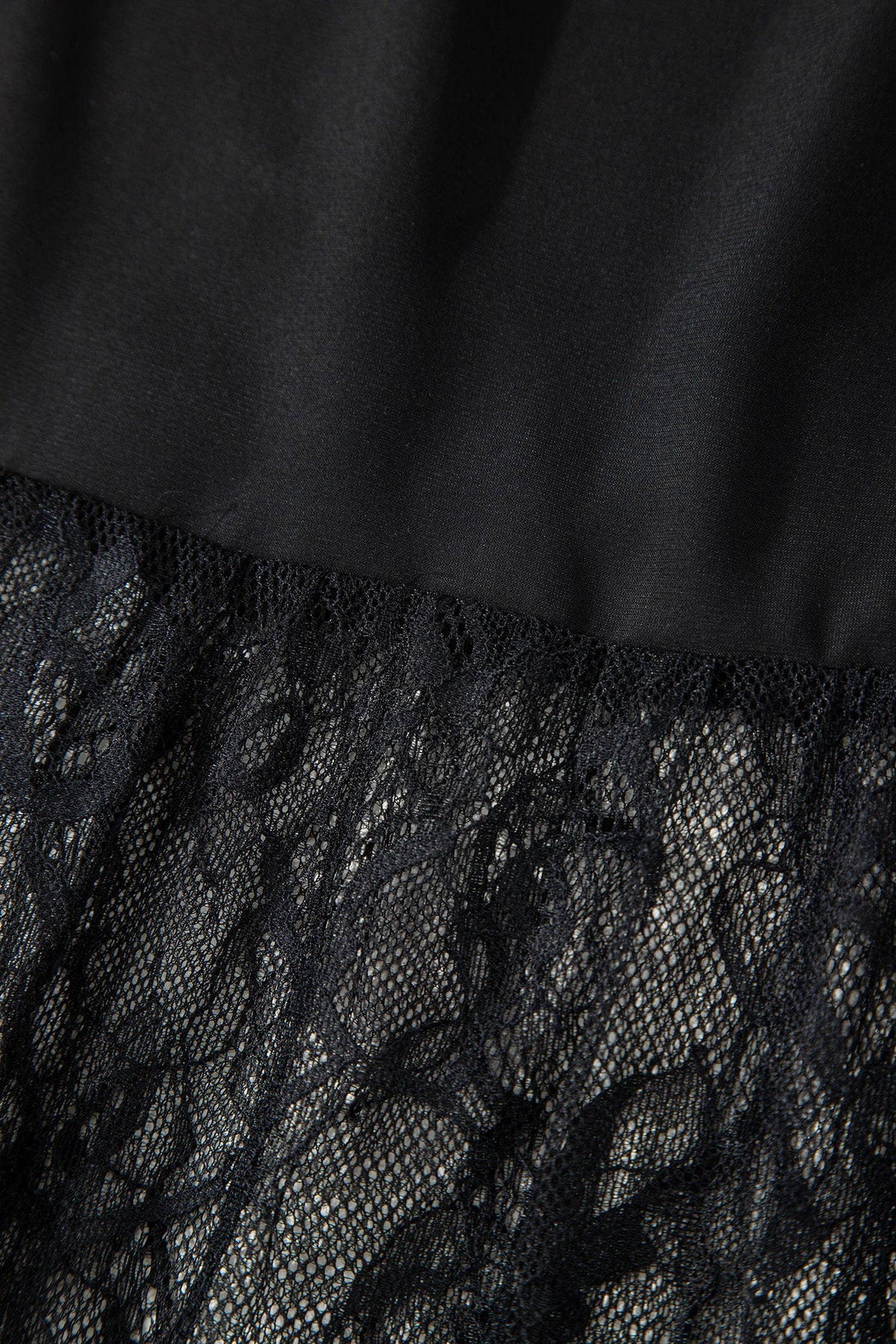 Close-up of black lace fabric with a plain background