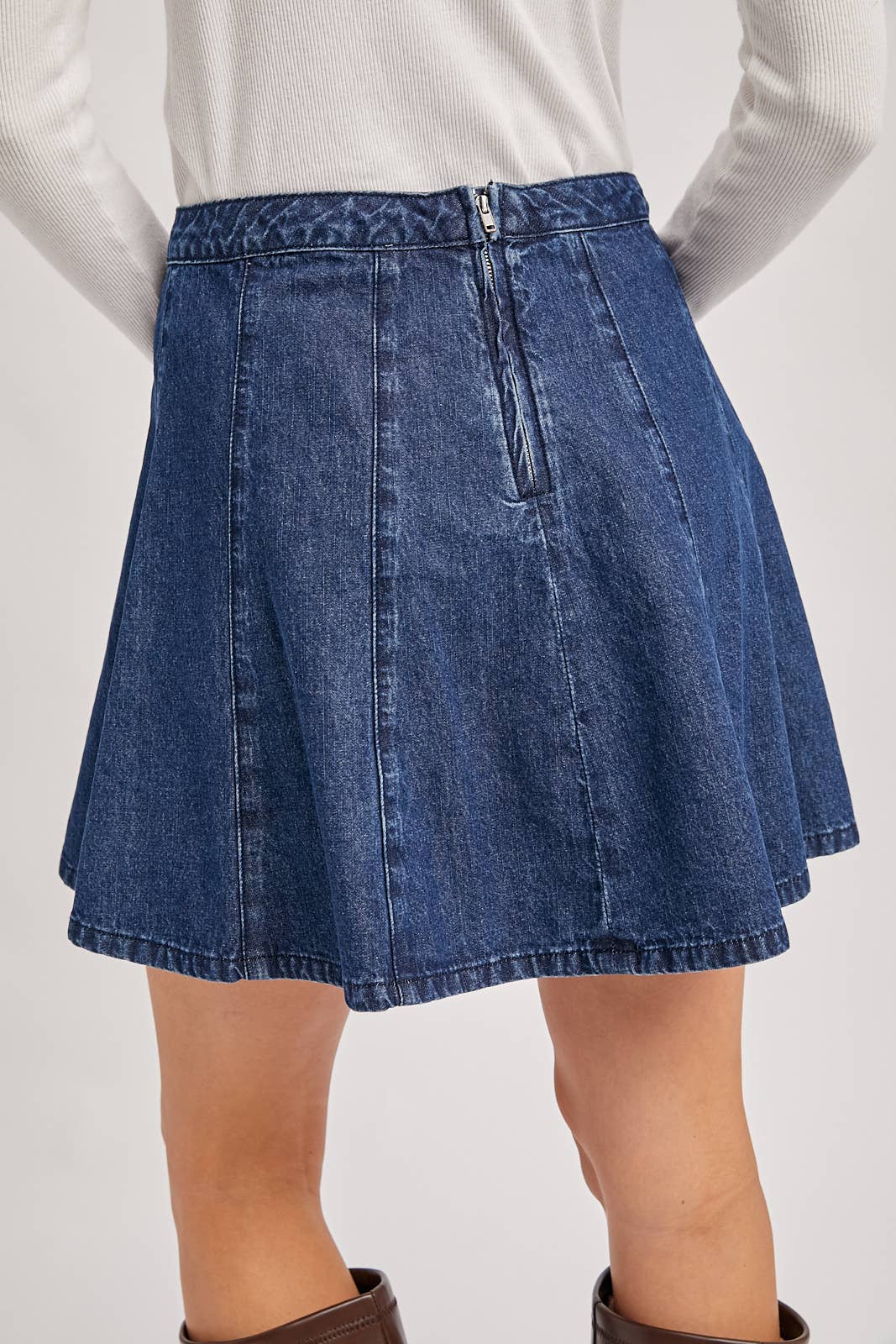 Blue denim skirt worn by a person on a white background