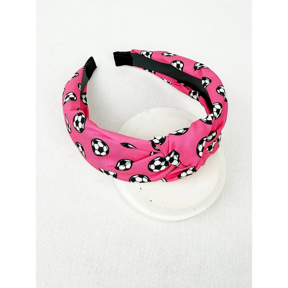 Pink headband with black and white soccer ball pattern on a white background