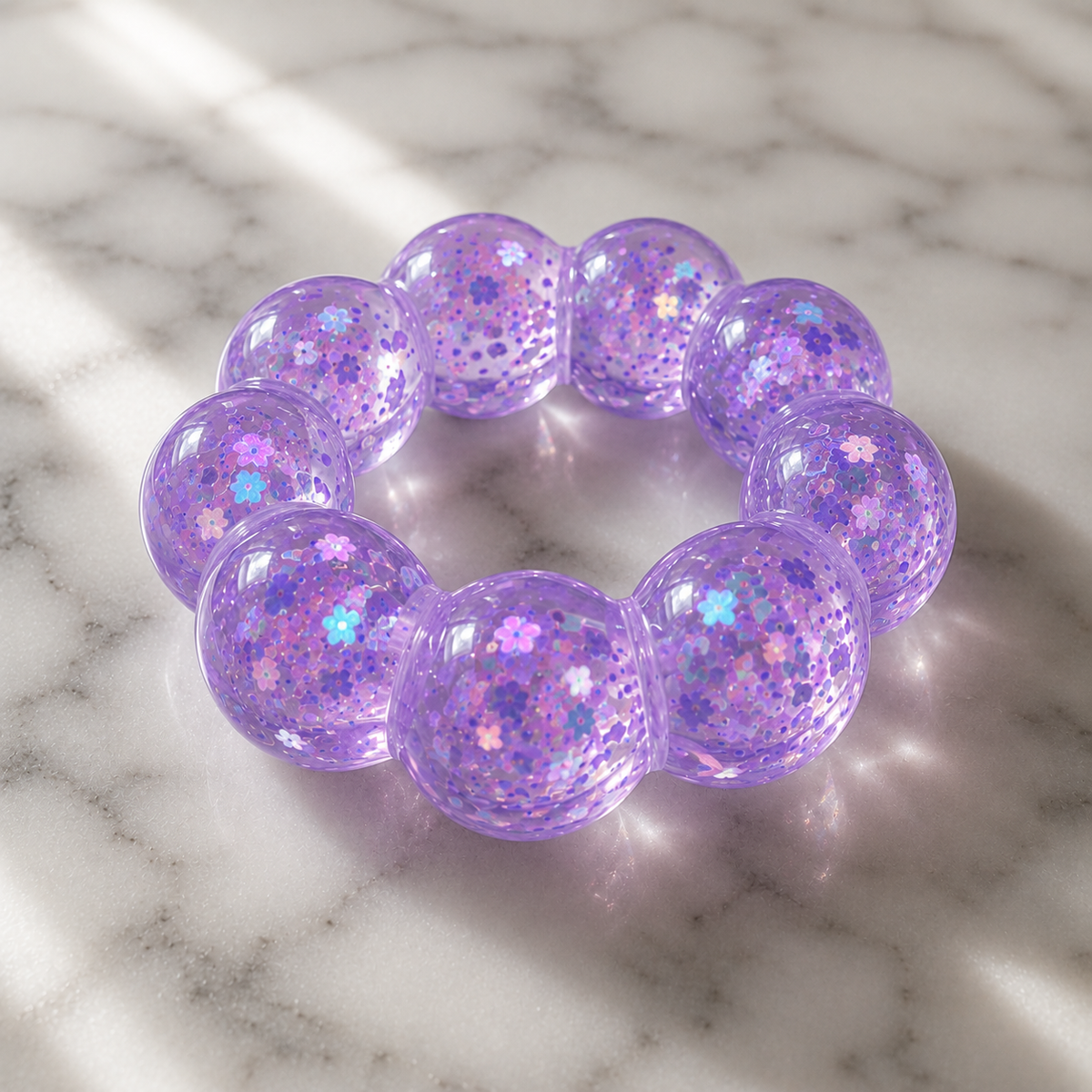 Purple glittery squishy bracelet on a marble surface